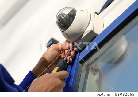 Technician installing CCTV camera on wall outdoors, closeup Technician installing CCTV camera on wall outdoors, closeup 93082065