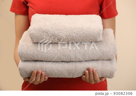 Woman holding fresh towels on color background, closeup 93082306