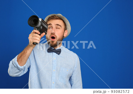 Young man with vintage video camera on blue background. Space for text Young man with vintage video camera on blue background. Space for text 93082572