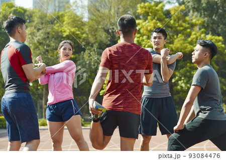 young asian adults warming up stretching ars and legs on track young asian adults warming up stretching ars and legs on track 93084476
