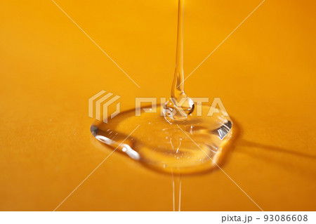 A drop of body gel or shampoo pouring from above on a yellow saturated background. 93086608