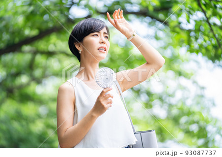 ハンディ扇風機を持つノースリーブの女性　扇風機　ビジネスウーマン　ビジネスマン 93087737