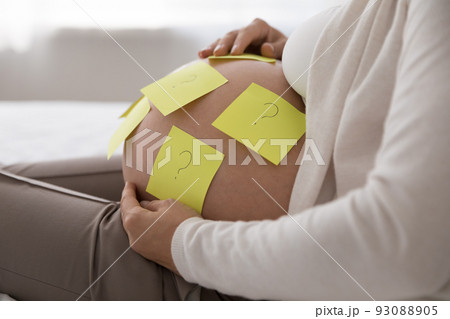 Attached sticky notes with questions on belly of pregnant woman 93088905