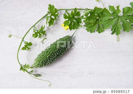 Bitter gourd or bitter melon with vine on wooden background. 93089317