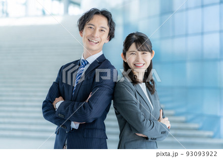 オフィスのロビーに背中合わせに立つ若いビジネスマンとビジネスウーマン オフィスのロビーに背中合わせに立つ若いビジネスマンとビジネスウーマン 93093922