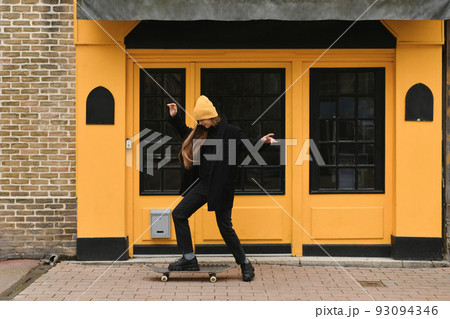 Girl in a yellow hat with a skateboard Girl in a yellow hat with a skateboard 93094346