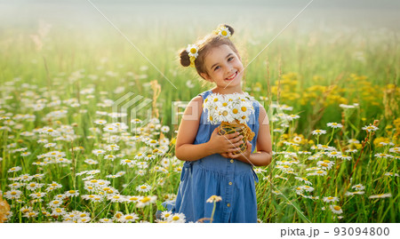 Pretty smiling little girl with a bouquet of daisies , stands in a field with daisies Pretty smiling little girl with a bouquet of daisies , stands in a field with daisies 93094800