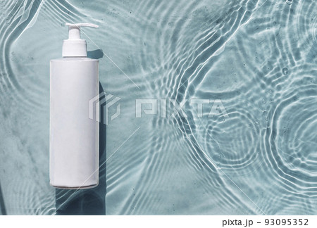 Cosmetic moisturizer with hyaluronic acid, micellar emulsion on blue water background with splashes. Mockup of cosmetic packaging 93095352