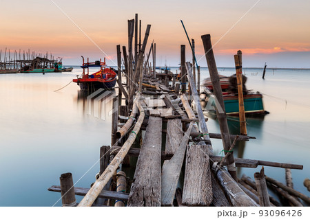 Old wood bridge for small fishing boat in the sea with sunset 93096426
