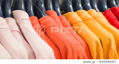 Photo of colorful clothes on hangers in shop Photo of colorful clothes on hangers in shop 93098697