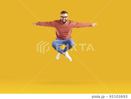 Excited energetic young Caucasian man jumping celebrating success posing in orange studio 93103693