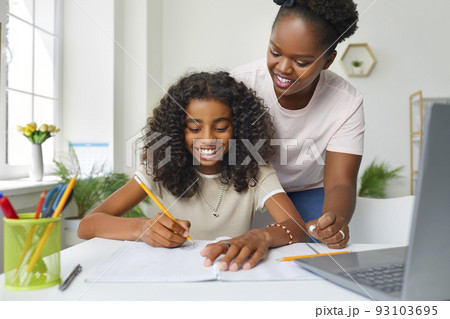 Joyful african american teenage girl doing school homework at home with mom's help. 93103695