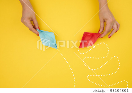 A woman's hand holds paper boats with different trajectories. 93104301