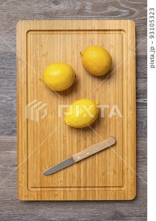 Three ripe lemons on a kitchen board 93105323