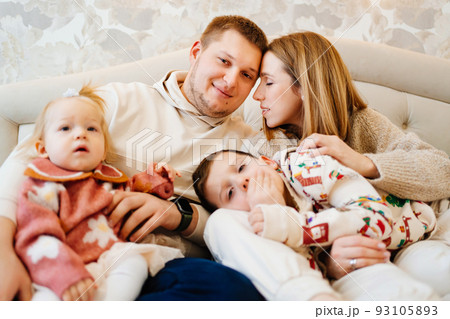 a loving family with two playful children lies in a cozy bed in the home bedroom a loving family with two playful children lies in a cozy bed in the home bedroom 93105893