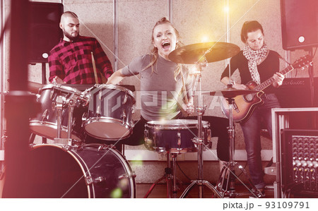Passionate emotional female drummer with her bandmates practicin Passionate emotional female drummer with her bandmates practicin 93109791