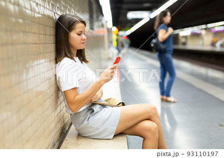 Female with phone waiting for subway train Female with phone waiting for subway train 93110197