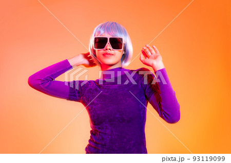 Metaverse concept. Young asian girl in purple shirt wearing sunglasses posing on the orange screen background Metaverse concept. Young asian girl in purple shirt wearing sunglasses posing on the orange screen background 93119099