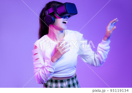 Young asian girl in white fashion shirt wearing vr headset watching playing and touching on the purple screen background Young asian girl in white fashion shirt wearing vr headset watching playing and touching on the purple screen background 93119134