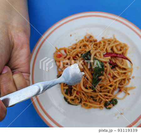 Asian woman using fork to scoop Spicy spaghetti pork.Drunken Spaghetti Thai call Popular street food 93119339