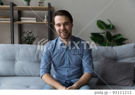 Smiling young man sit on sofa looking at camera 93121213
