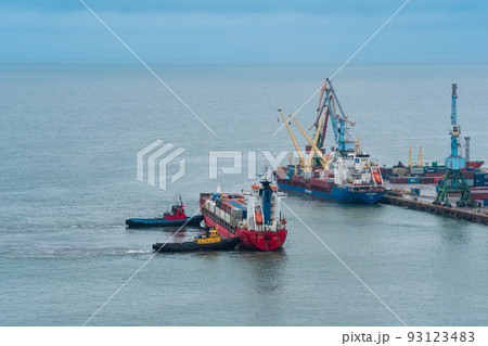 container ship is moored with the help of tugboats to a cargo berth, 93123483