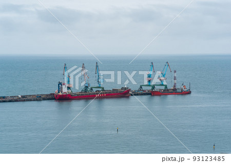 cargo berth with port cranes and moored ships against the backdrop of the open sea 93123485