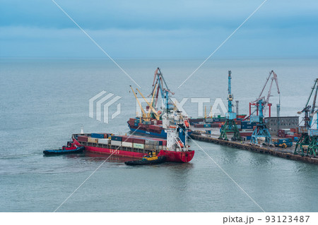 container ship is moored with the help of tugboats to a cargo berth container ship is moored with the help of tugboats to a cargo berth 93123487