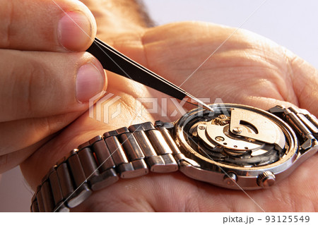 Watchmaker's job. Closeup male hands holding mechanical watches isolated over white background. Concept of vintage retro mechanisms, work, ad Watchmaker's job. Closeup male hands holding mechanical watches isolated over white background. Concept of vintage retro mechanisms, work, ad 93125549
