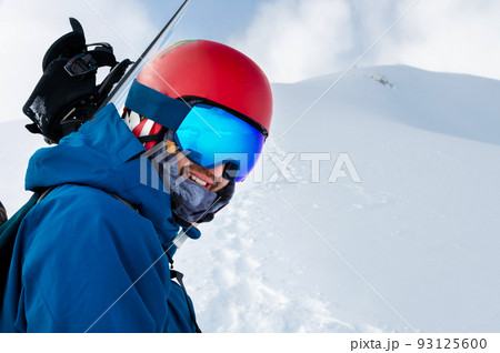 Equipped skier holding skis on his shoulder and looking directly at the camera, portrait. Man with winter equipment in the mountains at a ski resort Equipped skier holding skis on his shoulder and looking directly at the camera, portrait. Man with winter equipment in the mountains at a ski resort 93125600