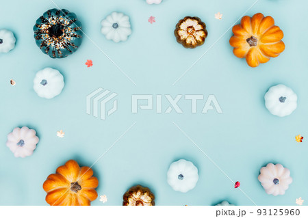 Trendy bright colorful Halloween background with border of orange, green, white, golden pumpkins on turquoise layout. Autumn, fall, halloween, thanksgiving day concept. Flat lay, top view, copy space 93125960