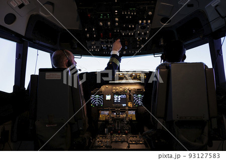 Male captain pushing dashboard buttons in plane cockpit, flying airplane jet with pilot and control panel command. Aircrew using engine power with switch and radar navigation on windscreen. Male captain pushing dashboard buttons in plane cockpit, flying airplane jet with pilot and control panel command. Aircrew using engine power with switch and radar navigation on windscreen. 93127583