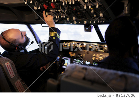 Male captain pushing buttons to start power on dashboard control, using panel command in cabin to fly airplane. Aircrew flying aircraft jet with radar compass and aerial navigation. Male captain pushing buttons to start power on dashboard control, using panel command in cabin to fly airplane. Aircrew flying aircraft jet with radar compass and aerial navigation. 93127606