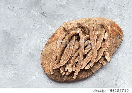 Slices of dried lingzhi mushroom, also called reishi or Ganoderma Lucidum, on a wooden board, gray background. Chinese traditional medicine product. Copy space. 93127719