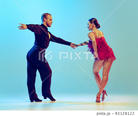 Dynamic portrait of professional dancers in stage attires dancing ballroom dance isolated on blue background. Concept of art, beauty, music, style. 93128122