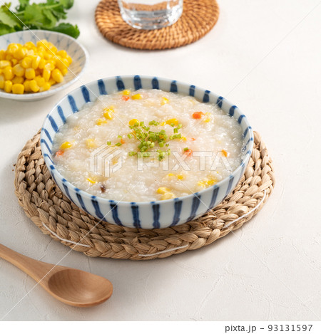 Delicious rice porridge congee with corn kernel and vegetables on white table background. Delicious rice porridge congee with corn kernel and vegetables on white table background. 93131597