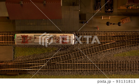 Diesel locomotive moving on model railroad. Top view of miniature of railway station. Diesel locomotive moving on model railroad. Top view of miniature of railway station. 93131813