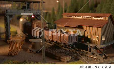 Model freight train arriving at railway station. Miniature railway station with moving cargo train. 93131818