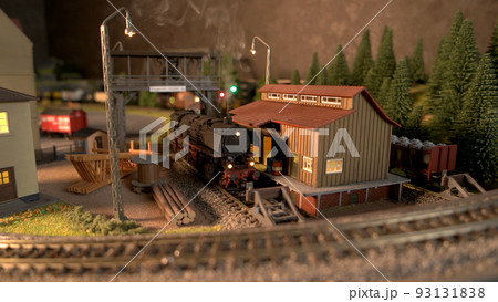 Model railway station with moving model locomotive. Toy diesel locomotive driving on railroad. Model railway exhibition. 93131838