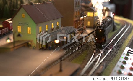 Steam engine replica entering the station. Model of steam train speeding through station. Miniature of city. Steam engine replica entering the station. Model of steam train speeding through station. Miniature of city. 93131848
