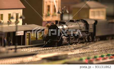 Model of railway station with moving train. Vintage old locomotive arrive at the station. 93131862