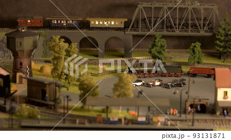 Model train moving on the bridge. Electric locomotive on the rail tracks. City in miniature. Model railway exhibition. Model train moving on the bridge. Electric locomotive on the rail tracks. City in miniature. Model railway exhibition. 93131871