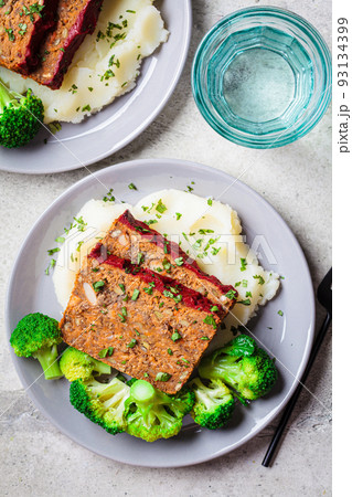Lentil meatloaf pieces with mashed potatoes and broccoli on gray plate. Vegan christmas recipe. Lentil meatloaf pieces with mashed potatoes and broccoli on gray plate. Vegan christmas recipe. 93134399