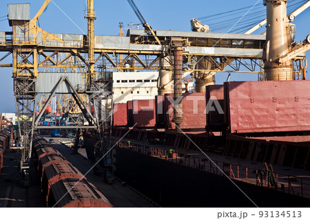 Loading grain into holds of sea cargo vessel in seaport from grain storage. Loading grain into holds of sea cargo vessel in seaport from grain storage. 93134513