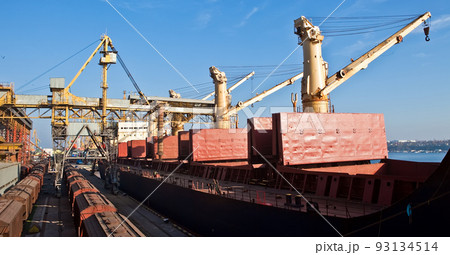 Loading grain into holds of sea cargo vessel in seaport from grain storage. Loading grain into holds of sea cargo vessel in seaport from grain storage. 93134514