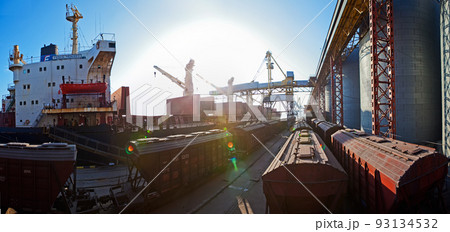 Loading grain into holds of sea cargo vessel in seaport from grain storage. Loading grain into holds of sea cargo vessel in seaport from grain storage. 93134532