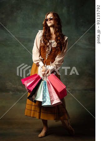 Vintage style portrait of pretty redhead woman with long curly hair like girl of renaissance eras, lady-peasant isolated on dark background. 93135792