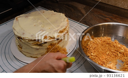 Cooking multi-layered cake Napoleon - baked cake layers, raw dough. Man covet cake sides by the crubms from the puffs 93136621