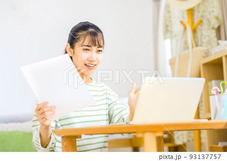 自宅で資料片手にチャットで説明するテレワーク中の若いビジネスウーマン 93137757