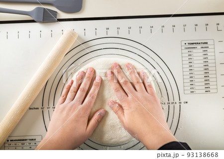 Kneading the dough on a silicone baking mat with round markings of different diameters to obtain a round shape, top view Kneading the dough on a silicone baking mat with round markings of different diameters to obtain a round shape, top view 93138668